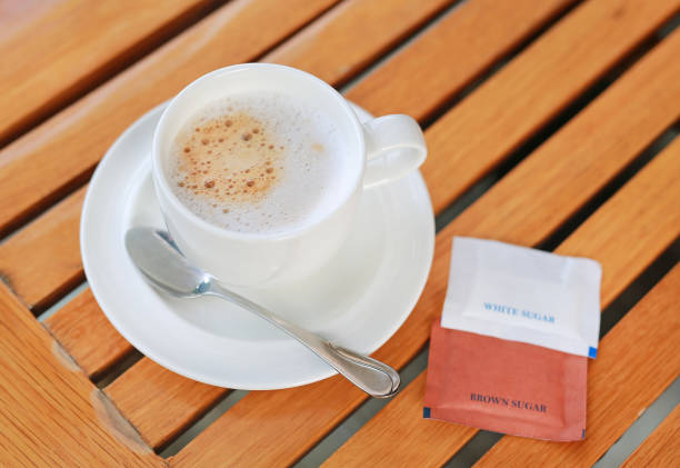 istock Cup of hot coffee with sugar envelopes on the wood table. 856866178