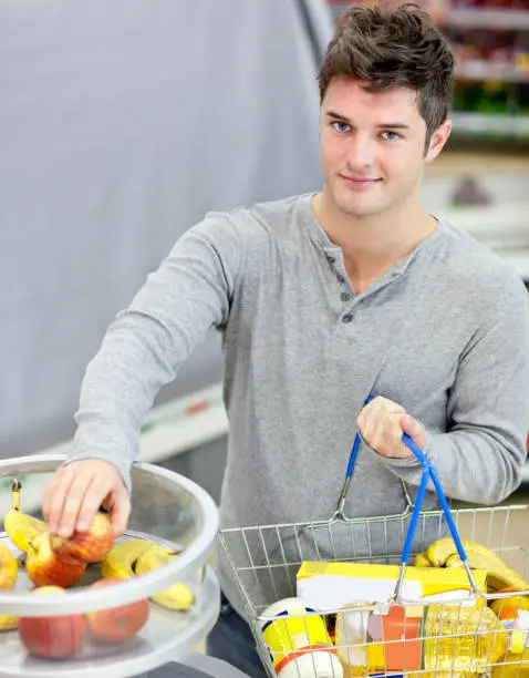 Healthy man with shoppingbasket buying fruits in a grocery shop