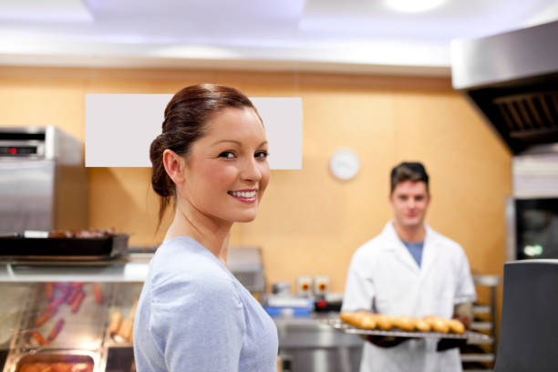 beautiful woman in a cafeteria buying baguette from a baker standing in his kitchen - 45876 imagens e fotografias de stock