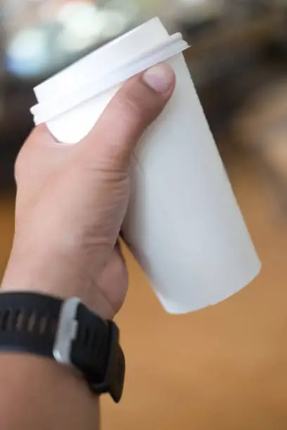 Hand holding take away paper hot coffee drinking cup