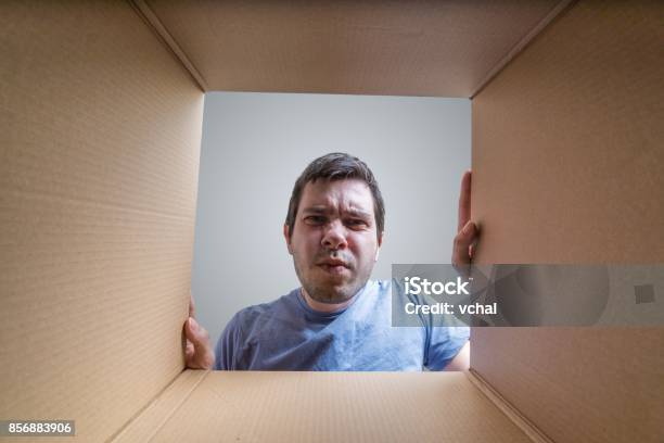 Young Disappointed Man Is Looking On Gift Inside Cardboard Box Stock Photo - Download Image Now
