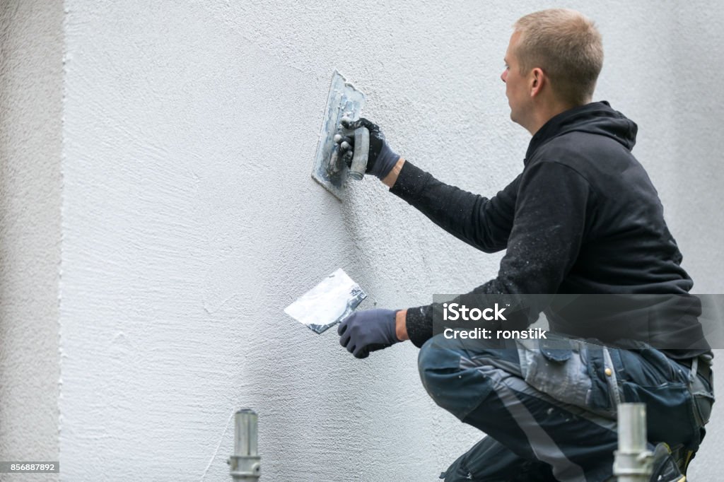 construction worker putting decorative plaster on house exterior Stucco Stock Photo