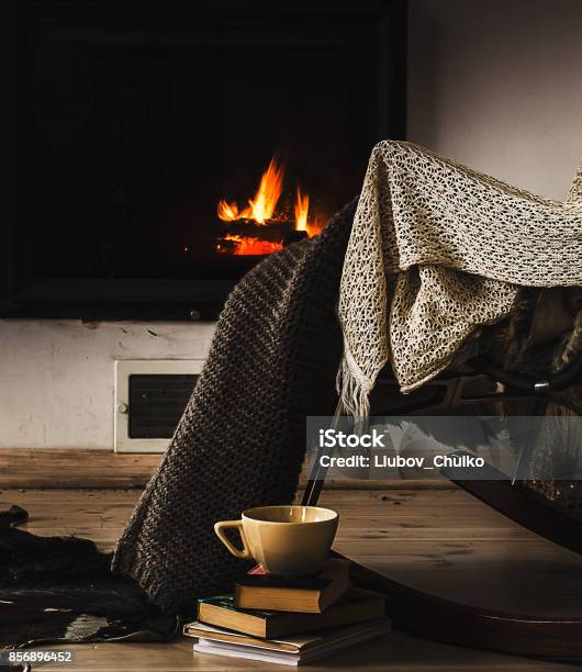 Rocking Chair With Knit Rug Books And Cup Of Tea Or Coffee Before Fireplace Stock Photo - Download Image Now