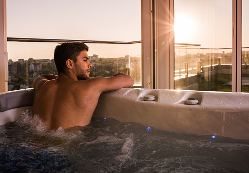Young man enjoying and relaxing in a hot tub.