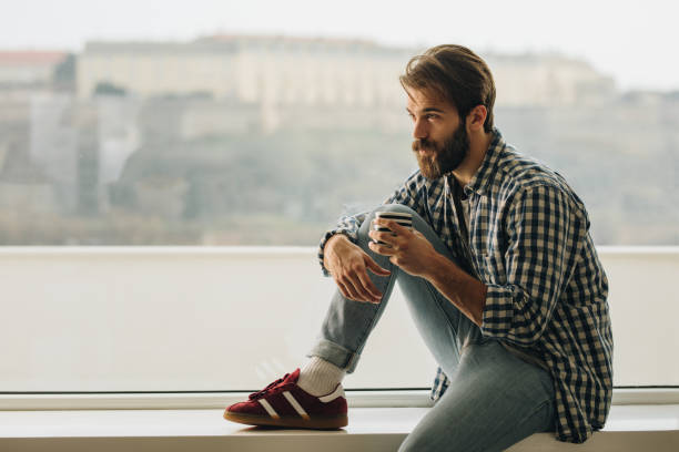 istock Serious man relaxing during coffee time by the window. 856912828