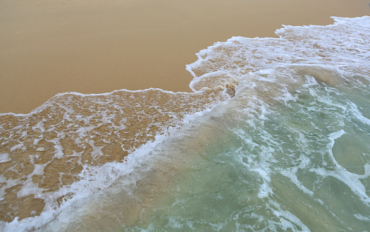 Surf wave is covering a sea beach sand.