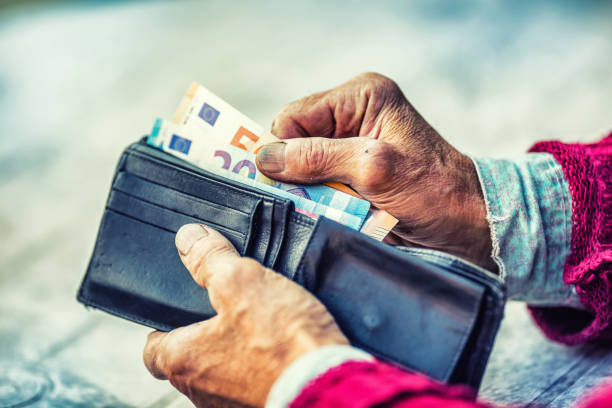 rentner-mann hält in händen brieftasche mit geld - women poverty senior adult mature adult stock-fotos und bilder