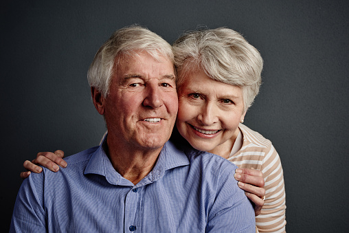 Horizontal studio shot on gray of young couple head and shoulders.