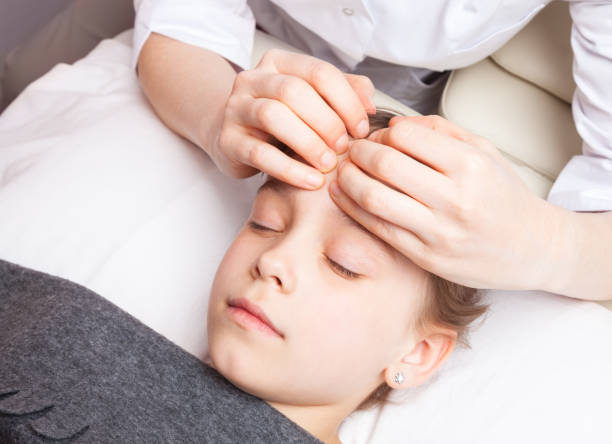 Girl receiving osteopathic treatment of her head stock photo