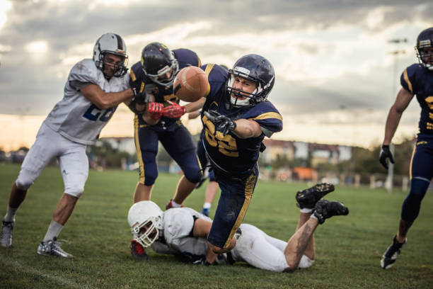 Making a touchdown! Determined American football player makes a touchdown after passing through defensive players. offense sporting position stock pictures, royalty-free photos & images