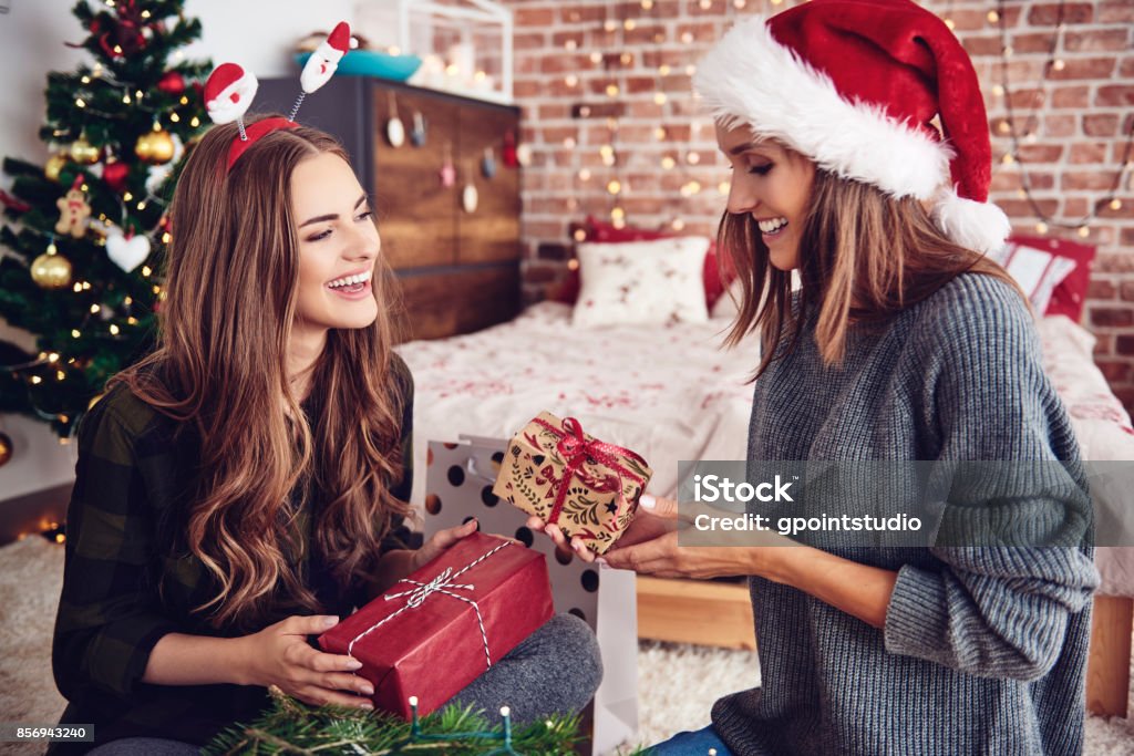 Amici che si presentano regali in camera da letto - Foto stock royalty-free di Regalo di Natale
