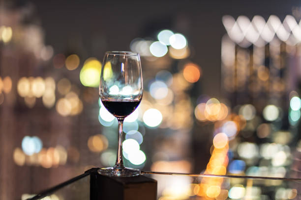 istock Wine glass with red wine in city bokeh background 856947904
