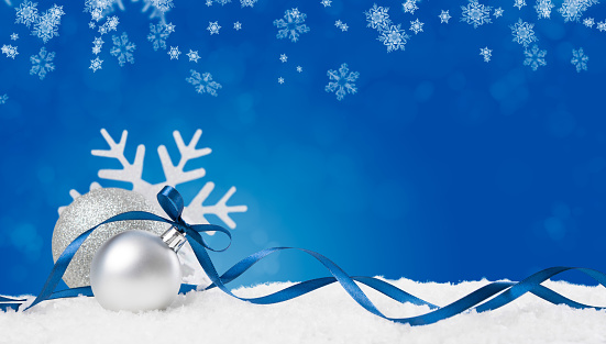 Christmas background in blue. Snow flakes and christmas balls with ribbon and copyspace. Xmas background with snowflakes, balls and ribbon. Write it on whatever you need.