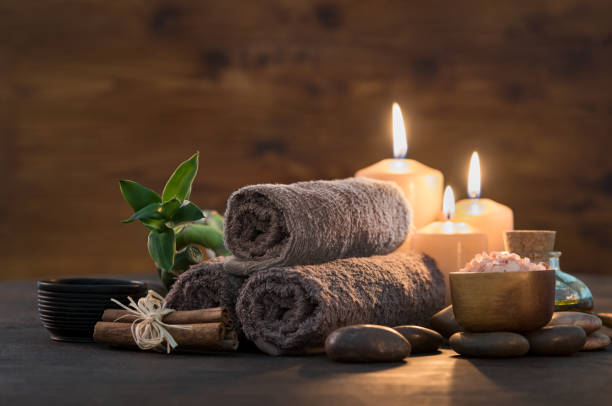 Beauty spa treatment with candles Brown towels with bamboo and candles for relax spa massage and body treatment. Beautiful composition with candles, spa stones and salt on wooden background. Spa and wellness setting ready for beauty treatment. spa stock pictures, royalty-free photos & images