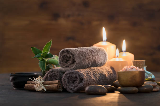 Beauty spa treatment with candles Brown towels with bamboo and candles for relax spa massage and body treatment. Beautiful composition with candles, spa stones and salt on wooden background. Spa and wellness setting ready for beauty treatment. health farm stock pictures, royalty-free photos & images