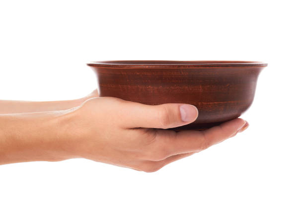 istock clay empty brown bowl in hand isolated on white background 856952902