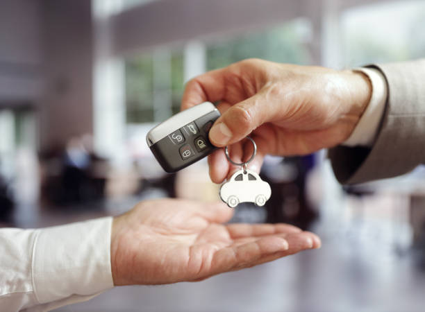 salesman handing over the keys to the customer who just rented the car