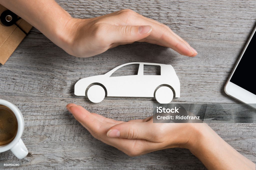Car insurance concept Hands protecting icon of car over wooden table. Top view of hands showing gesture of protecting car. Car insurance and automotive business concept. Car Insurance Stock Photo