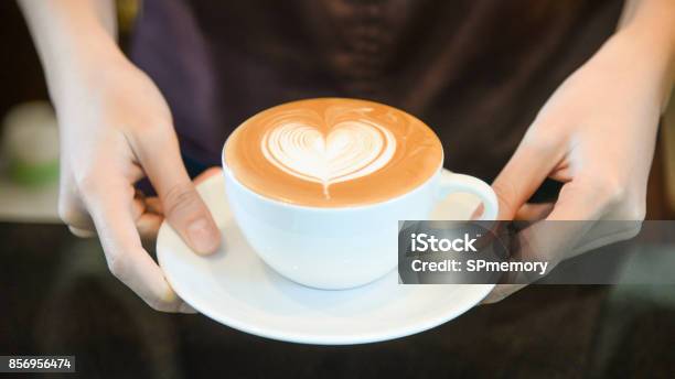 Woman Serving Coffee While Standing In Coffee Shop Focus On Latte Art Hearth Shape Cup In Female Hands While Placing Of Coffee On Counter Stock Photo - Download Image Now