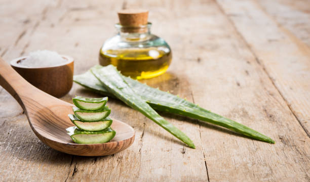 Aloe spa treatment Close up of aloe vera leaves and essential oil on wooden background. Spa and beauty treatment concept with green aloe vera on wooden spoon. Fresh slices of aloe with essential oil. aloe plant alternative medicine body care stock pictures, royalty-free photos & images