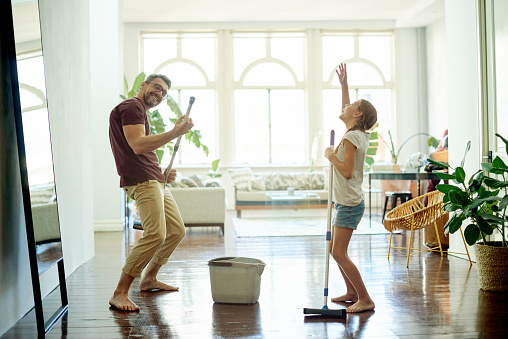 Shot of a handsome mature man and his daughter mopping the floors in their home as part of their spring cleaning