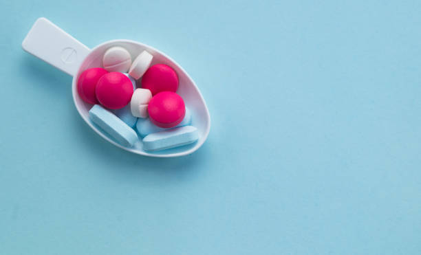 istock colorful color pills in the tablespoon on blue background 856989830