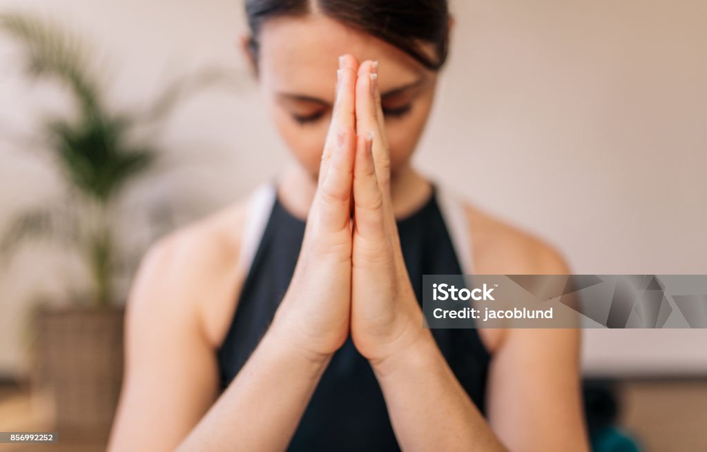 Woman in namaste yoga pose meditating Close up of woman hands joined. Female meditating with her hands joined indoors. Namaste yoga pose, meditating, breathing and relaxing. Hand Stock Photo