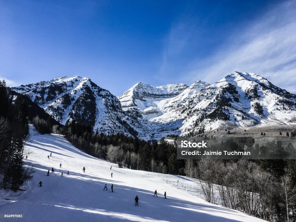 people skiing down a mountain skiers on the side of a mountain in Winter Utah Stock Photo