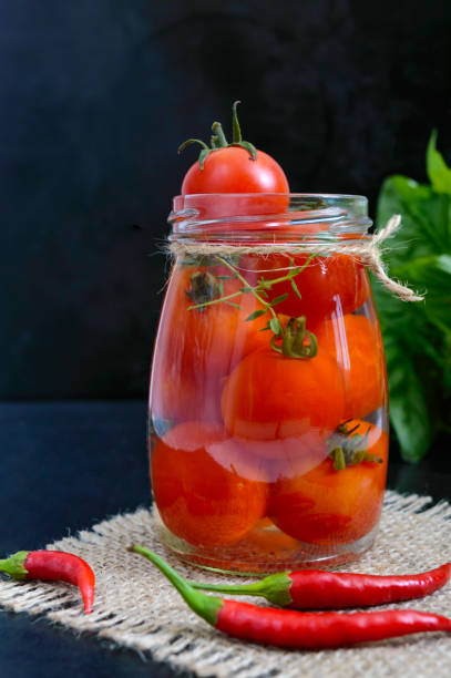 istock Sour tomatoes in a glass jar on a black background. Pickles. 857010142