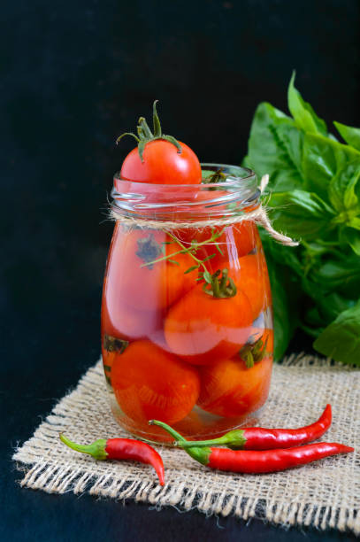 istock Sour tomatoes in a glass jar on a black background. Pickles. 857010164