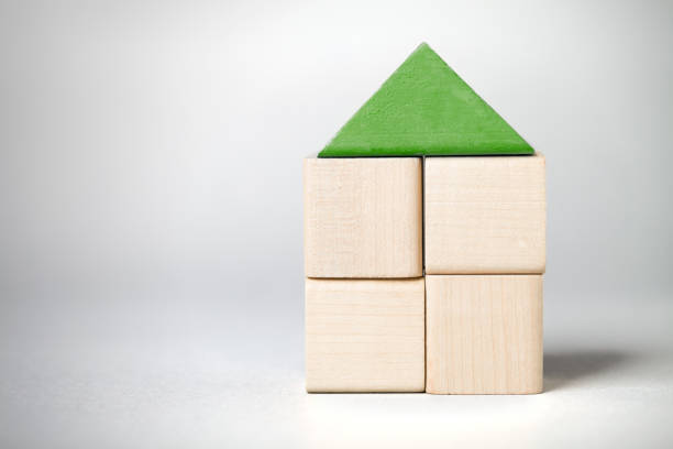 Wooden toy house on on grey background. On left is empty space to put text or something else. This file is cleaned and retouched.