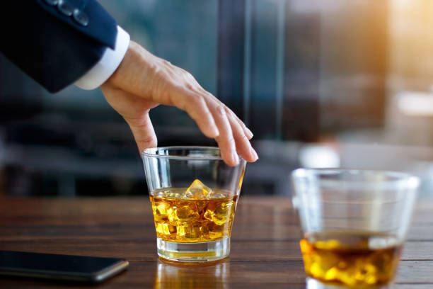 Hand of businessman touching glass of bourbon whiskey in building background Hand of businessman touching glass of bourbon whiskey in building background glass of bourbon stock pictures, royalty-free photos & images