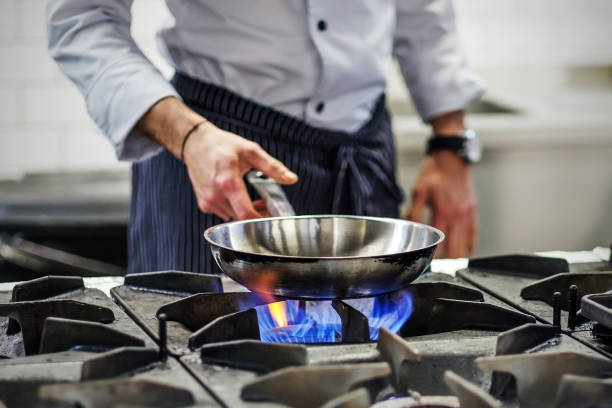 Chef controls the cooking process Frying pan on a gas stove. Chef controls the cooking process pan stock pictures, royalty-free photos & images