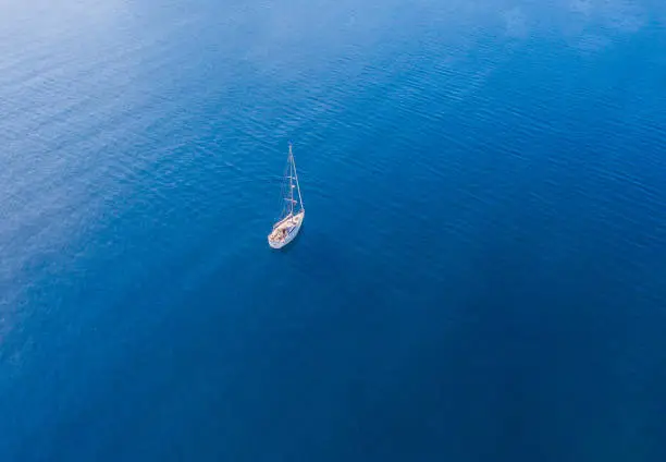 Photo of A lone sailing boat at anchor. The view from the air. Drone photo