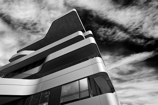 Low angle view of a modern office building in Düsseldorf and fluffy clouds, high contrast black and white photograph.