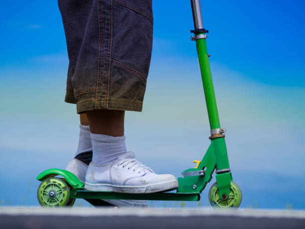 istock Boys big feet in white sneakers on a green scooter. 857032160