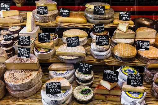 Paris, France - Jule 09, 2017:  A large selection of different french and italian cheeses on the counter of a small store at the Aligre Market (Marche d'Aligre) in the Bastille district.\