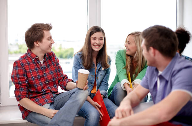 education, people, friendship, communication and learning concept - group of happy international high school students or classmates with folders and coffee talking