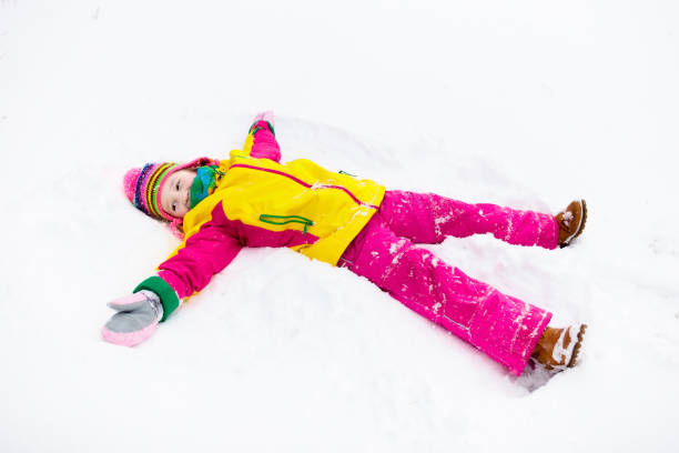 bambino che fa l'angelo della neve. i bambini giocano nel parco invernale. - 13417 foto e immagini stock