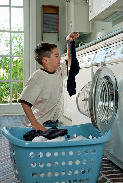 humorous picture of boy doing laundry chores - the phoenix of wits fotografías e imágenes de stock