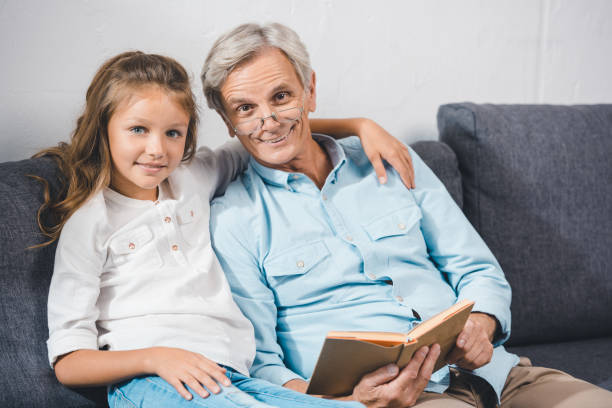 istock grandfather and granddaughter reading book 857049216