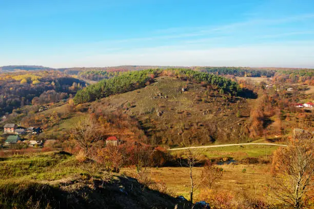 View on the beautiful colorful autumn landscape of the hills with trees and greenfields in the countryside.