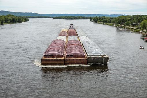 Towboat pushing the barge with freight on the Mississippi River midsummer.