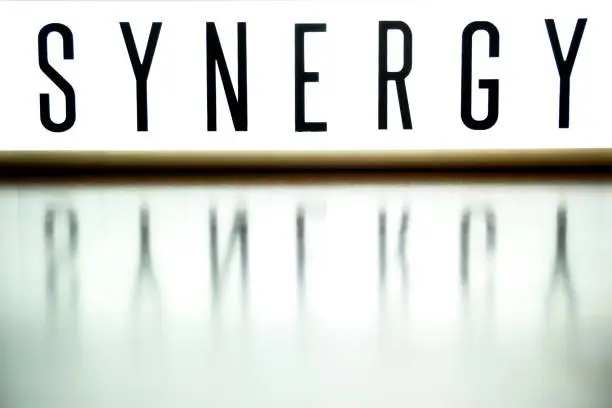Photo of A light up board displays the phrase SYNERGY