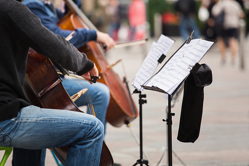 A group of musicians playing cellos on a street in a European city