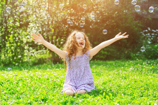 istock Laughing curly girl enjoy soap bubbles. 857083362