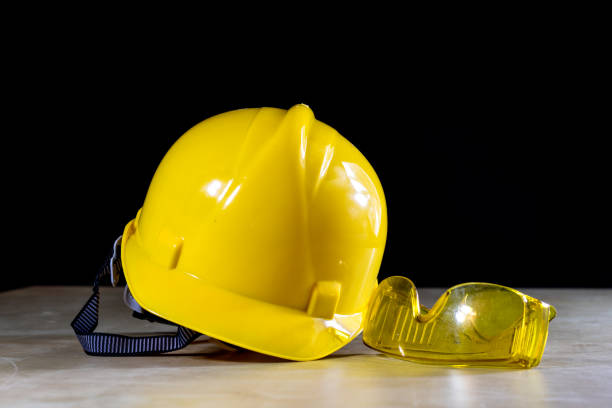 istock Workwear, helmet, gloves and glasses on a wooden working table. Place workshop, black background. 857090268