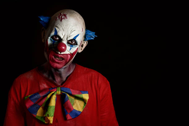 scary evil clown closeup of a scary evil clown wearing a dirty and ragged costume with a blank black space on the right clown photos stock pictures, royalty-free photos & images