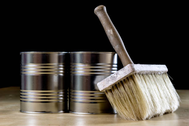 istock Cans of paint on a wooden workshop table. Next to the pedals and paint rollers. Black background 857098492