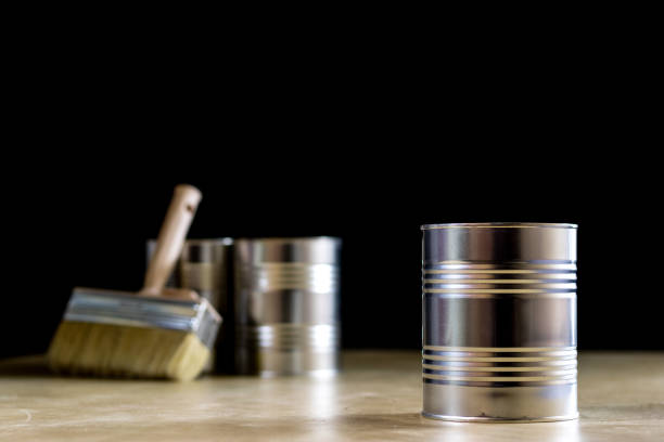 istock Cans of paint on a wooden workshop table. Next to the pedals and paint rollers. Black background 857099572